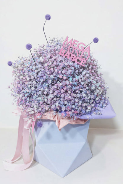 „Pastelowy flower box z kolorową gipsówką w odcieniach różu, fioletu i błękitu, w niebieskim pudełku z kokardą.”