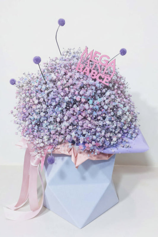 „Pastelowy flower box z kolorową gipsówką w odcieniach różu, fioletu i błękitu, w niebieskim pudełku z kokardą.”